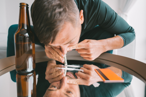 man snorting powered cocaine off of a glass table