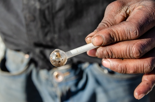 man holding up a meth pipe