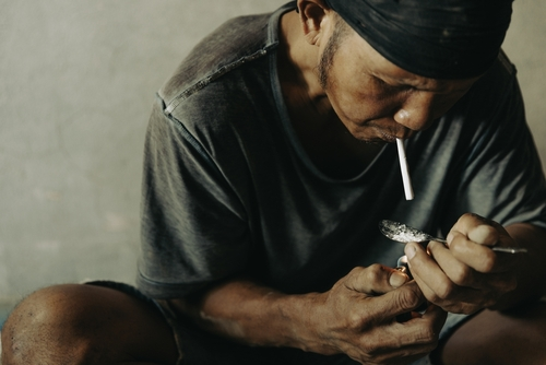 man sitting down smoking meth