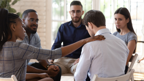 people comforting man in therapy