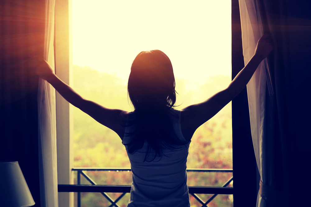 woman opening up a curtain
