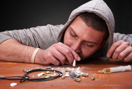man snorting pills on a table with a syringe on the table