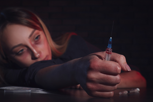 woman holding a syringe after using it, drug addict