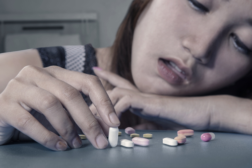 woman looking high while touching pills