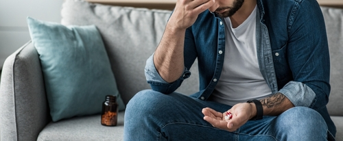 man sitting on couch with pills in hand