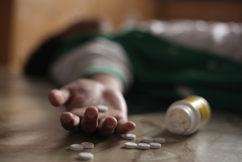 man laying on floor with pills around him 