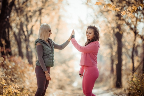 two women high fiving after a workout in nature