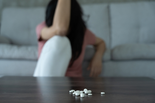 woman sitting with pills on the table in front of her