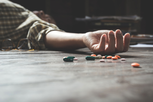 person laying on ground after taking pills