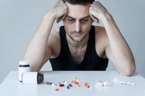 man staring at a bunch of pills on a table