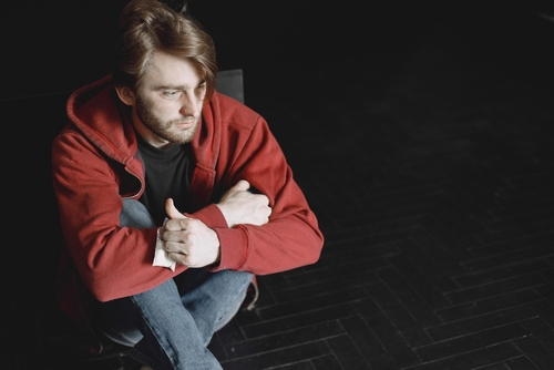 man sitting down while holding a baggie of cocaine