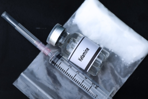 a vial of ketamine next to a syringe