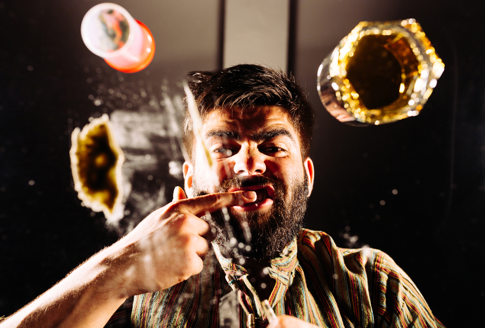 man looking down while rubbing cocaine on his gums