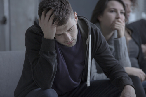 man sitting looking depressed with his head down