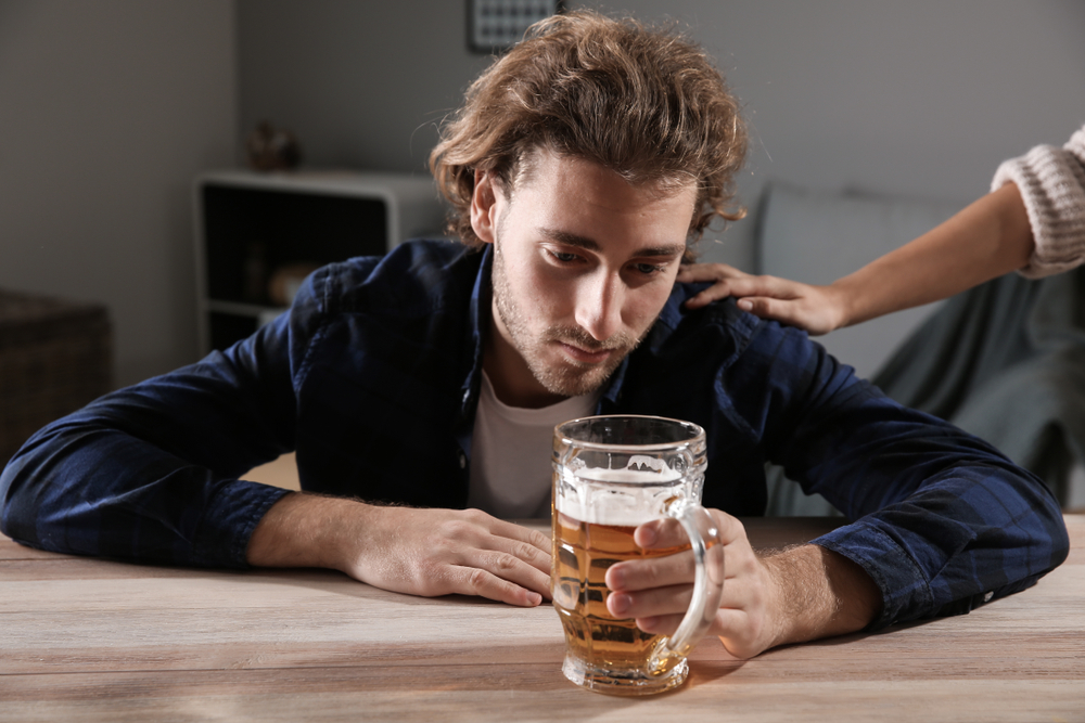 person helping an alcoholic who doesn't want help